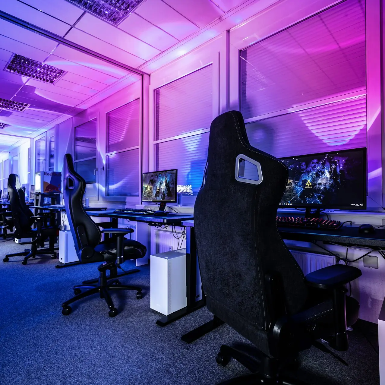a room filled with lots of computer desks and chairs